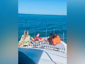 A group of friends relaxes on the deck of a boat, enjoying the stunning ocean views — a perfect moment for socializing and unwinding on the water.