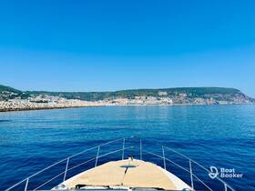 A stunning view from the front of a boat cruising through calm waters, showcasing a picturesque coastline under a clear blue sky.