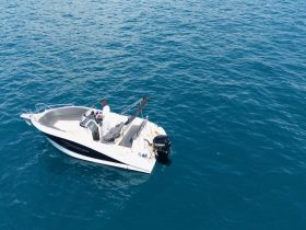 A captain navigates a sleek boat through clear blue waters, showcasing the perfect day for a boating adventure.