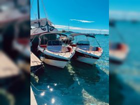 Two boats docked at a marina under a clear blue sky, showcasing their vibrant designs and the serene waters of the harbor.