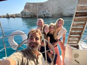 A joyful family poses for a selfie on a boat, surrounded by stunning coastal scenery — a perfect moment capturing their boating adventure.