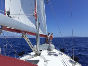 A couple enjoys a sailing adventure on a beautiful day, showcasing the thrill of being out on the open ocean.