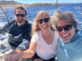 A joyful group enjoys a sailing adventure on the open ocean, capturing smiles and camaraderie against a stunning backdrop of blue waters.