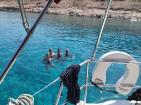 A joyful group enjoys swimming in crystal-clear waters, creating unforgettable memories on their boating adventure.