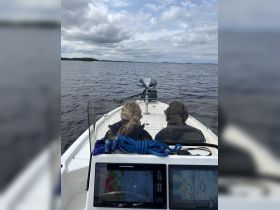 Two individuals enjoy a scenic boat ride, taking in the tranquil waters and cloudy skies — perfect for a day of exploration on the water.