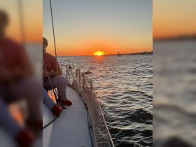 A serene sunset view from a sailboat, with a guest enjoying the moment as the sun dips below the horizon — perfect for romantic evening sails or peaceful getaways on the water.