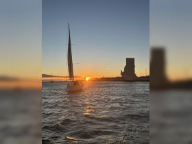 A sailboat glides through the harbor at sunset, creating a picturesque scene perfect for evening cruises and romantic getaways.