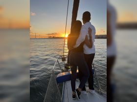 A couple enjoys a romantic sunset view from their sailboat, creating the perfect backdrop for memorable moments on the water.