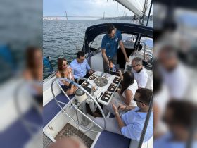 A lively group enjoys a gourmet meal and drinks aboard a yacht, with stunning views of the bridge in the background — perfect for celebrations and social gatherings on the water.