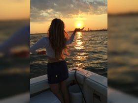 A woman enjoys a stunning sunset on a boat, creating a picturesque moment perfect for romantic outings or sunset cruises.
