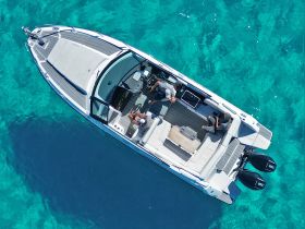 Aerial view of a stylish boat with guests onboard, enjoying the clear turquoise waters — perfect for a day of relaxation and adventure on the sea.
