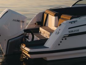 A close-up view of the Noblesse boat featuring a Mercury engine, showcasing its sleek design and hull in calm waters.