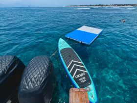 A paddleboard and a floating mat are anchored in clear turquoise waters, perfect for a day of fun and relaxation on the water.