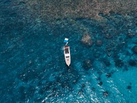 An aerial view of a boat anchored in crystal-clear waters, surrounded by vibrant coral reefs, showcasing the beauty of marine life and perfect for snorkeling adventures.