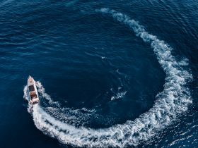 A thrilling aerial view of a speedboat making sharp turns in deep blue waters, showcasing the excitement of on-water adventures.
