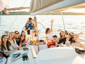 A joyful group celebrates aboard a sailboat, enjoying cocktails and a beautiful sunset — perfect for memorable gatherings and special occasions on the water.