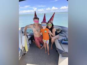 A joyful family celebrates a birthday on a boat, wearing festive hats and sunglasses, creating unforgettable memories on the water.