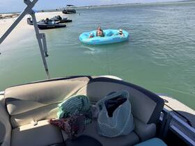 Guests enjoy a fun day on the water, relaxing in a floating mat while anchored near a sandy beach — perfect for summer outings and group adventures.