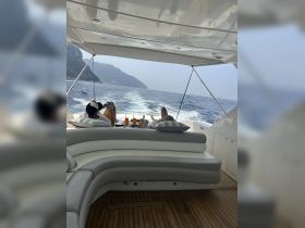 Guests relax on a luxurious yacht, enjoying cocktails and stunning coastal views — a perfect setting for a day on the water.