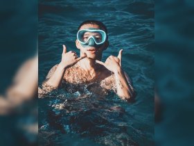 A young man enjoys snorkeling in clear ocean waters, showcasing a fun and adventurous spirit perfect for water activities.