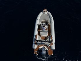 Aerial view of a sleek speedboat navigating through deep blue waters, showcasing its stylish design and spacious deck.