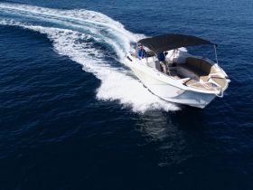 A sleek speedboat glides through deep blue waters, showcasing its elegant design and performance on the open sea.