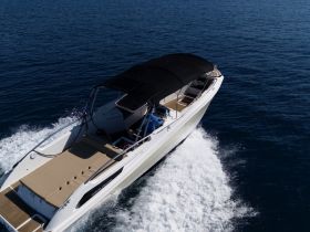 A sleek speedboat cruising through clear waters, showcasing its stylish design and spacious deck — perfect for thrilling adventures on the open sea.