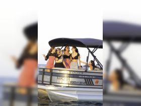 A lively group of friends enjoys a fun moment aboard a pontoon boat, celebrating together on the water — perfect for memorable outings and parties.
