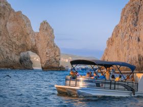 A lively group enjoys a scenic boat tour near the iconic rock arch in Cabo San Lucas, capturing the beauty of the coastline and the joy of exploration.