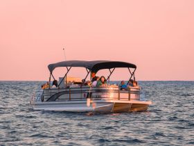 A lively group enjoys a sunset cruise aboard a pontoon boat, creating memorable moments on the water.