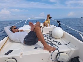 A man relaxes on a boat with his dog enjoying the ocean view — a perfect moment of leisure on the water.