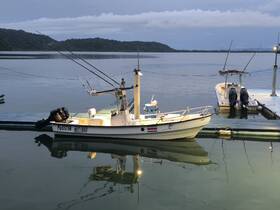 A fishing boat docked peacefully at twilight, reflecting on calm waters — a serene scene perfect for fishing enthusiasts.