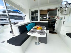 A cozy dining area inside a yacht featuring comfortable seating and a beautifully arranged fruit platter, perfect for enjoying meals while at sea.