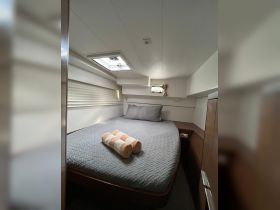 Cozy cabin interior featuring a comfortable bed and neatly arranged towels, perfect for relaxing on a boating adventure.