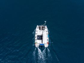 Aerial view of a sleek catamaran cruising through deep blue waters, perfect for exploring coastal destinations or enjoying a day on the sea.
