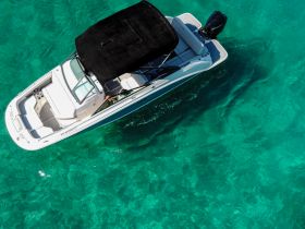 Aerial view of a sleek speedboat cruising through crystal-clear waters, showcasing the perfect vessel for a day of adventure on the sea.