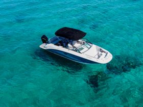 Aerial view of a sleek speedboat cruising through crystal-clear turquoise waters, perfect for a day of adventure on the sea.