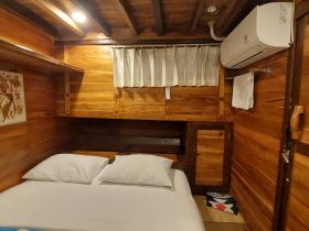 Cozy interior of a boat cabin featuring a comfortable bed and wooden decor, perfect for relaxing during your maritime adventures.