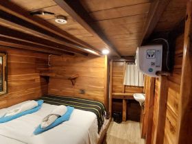 Cozy interior cabin of a boat featuring a double bed with decorative towels and wooden accents, perfect for a comfortable stay on the water.