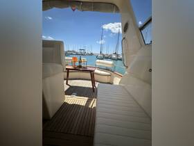 A cozy interior view of a boat featuring comfortable seating and a table set for drinks, perfect for relaxing on the water.