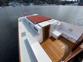 A spacious interior view of a boat featuring comfortable seating and elegant wooden flooring, perfect for relaxing on the water.