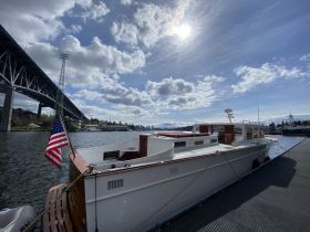 A beautiful yacht docked with an American flag waving, set against a backdrop of clouds and a bridge, perfect for showcasing waterfront adventures.