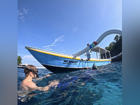 A child snorkels in clear waters near the boat 'MR. NOBODY,' creating a perfect family adventure in a tropical paradise.