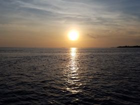 A stunning sunset over calm waters, creating a picturesque scene perfect for evening boat cruises or romantic getaways.