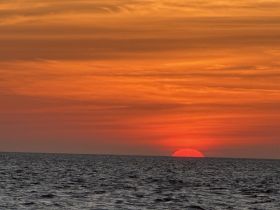 A stunning sunset over the ocean, creating a picturesque backdrop for evening boat cruises and tranquil moments on the water.