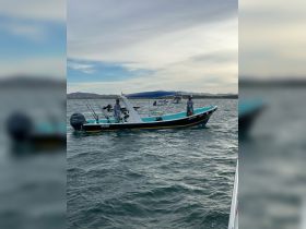Two fishermen aboard a boat navigate the waters, showcasing an active fishing experience — perfect for adventure seekers looking to reel in their catch.
