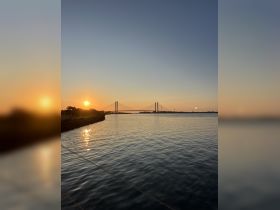A stunning sunset view over the water, featuring a bridge silhouetted against the vibrant sky — perfect for capturing the beauty of evening boat trips.