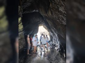 A group of adventurers explores a stunning cave, creating unforgettable memories during their beach excursion.