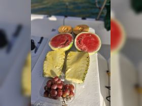 A vibrant display of fresh fruits including watermelon, pineapple, and grapes, perfect for enjoying on a boat trip.