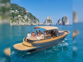 A lively group enjoys a day on a stylish boat near the stunning coastline of Capri, capturing the essence of luxury and celebration on the water.